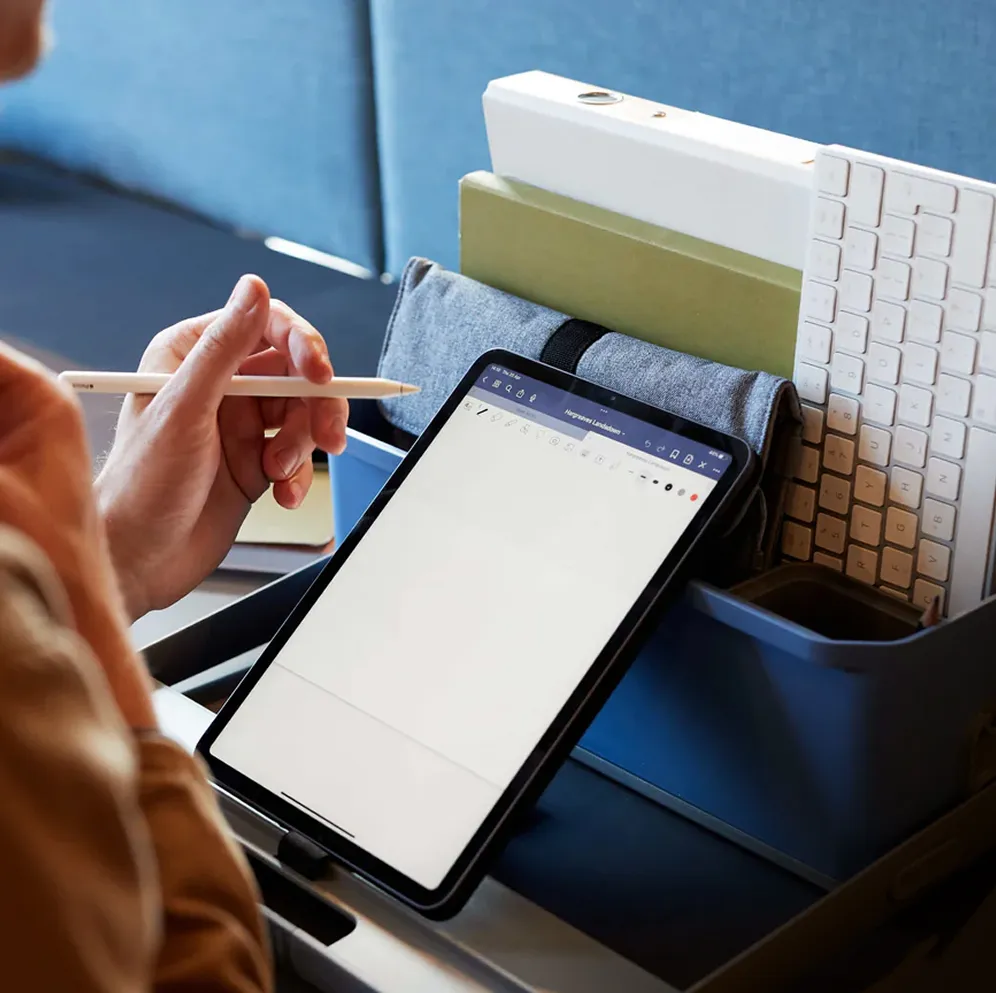 Une personne tient un crayon et écrit sur une tablette.