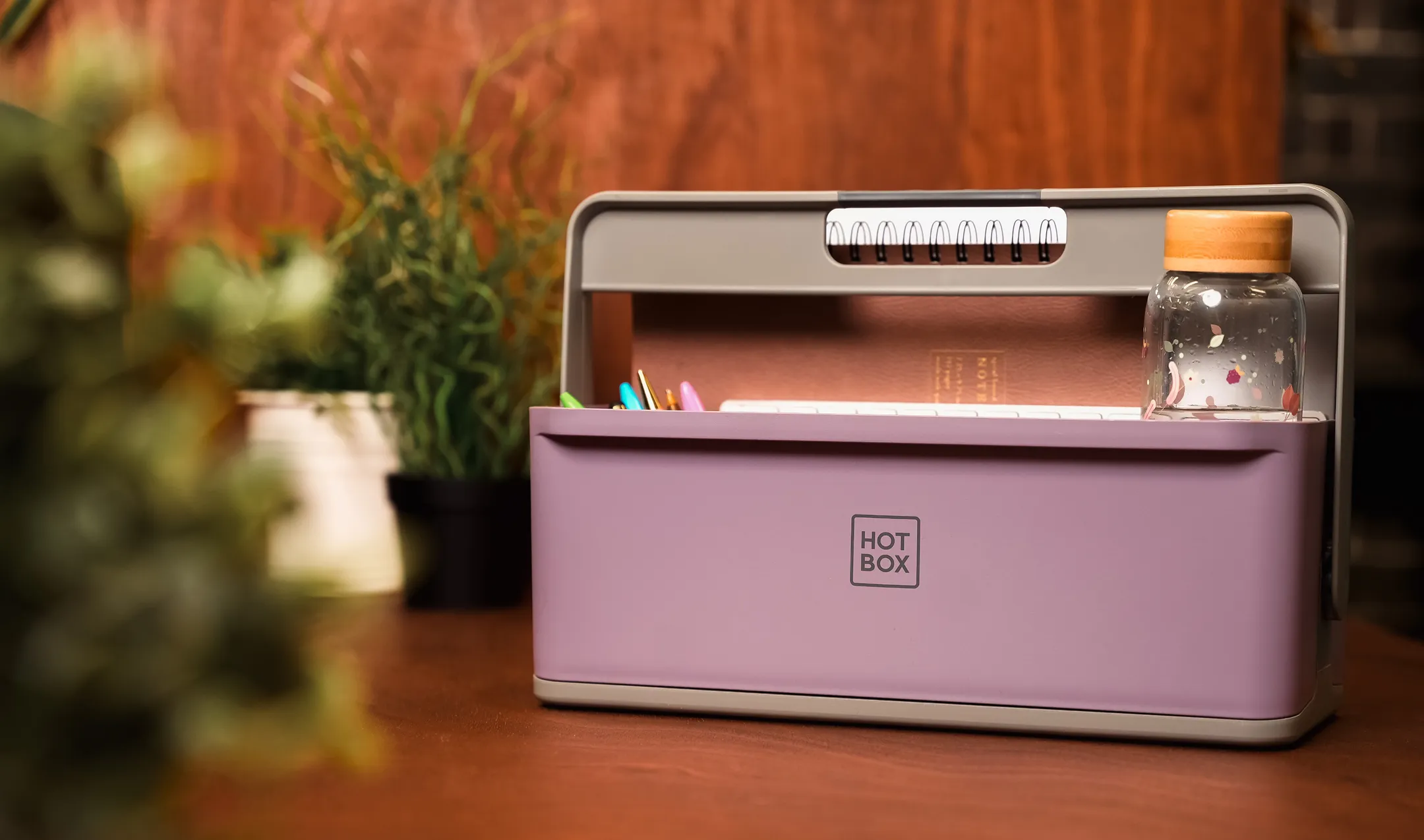 Pink Hotbox Mini 4 desk caddy sitting on a desk with greenery around it.