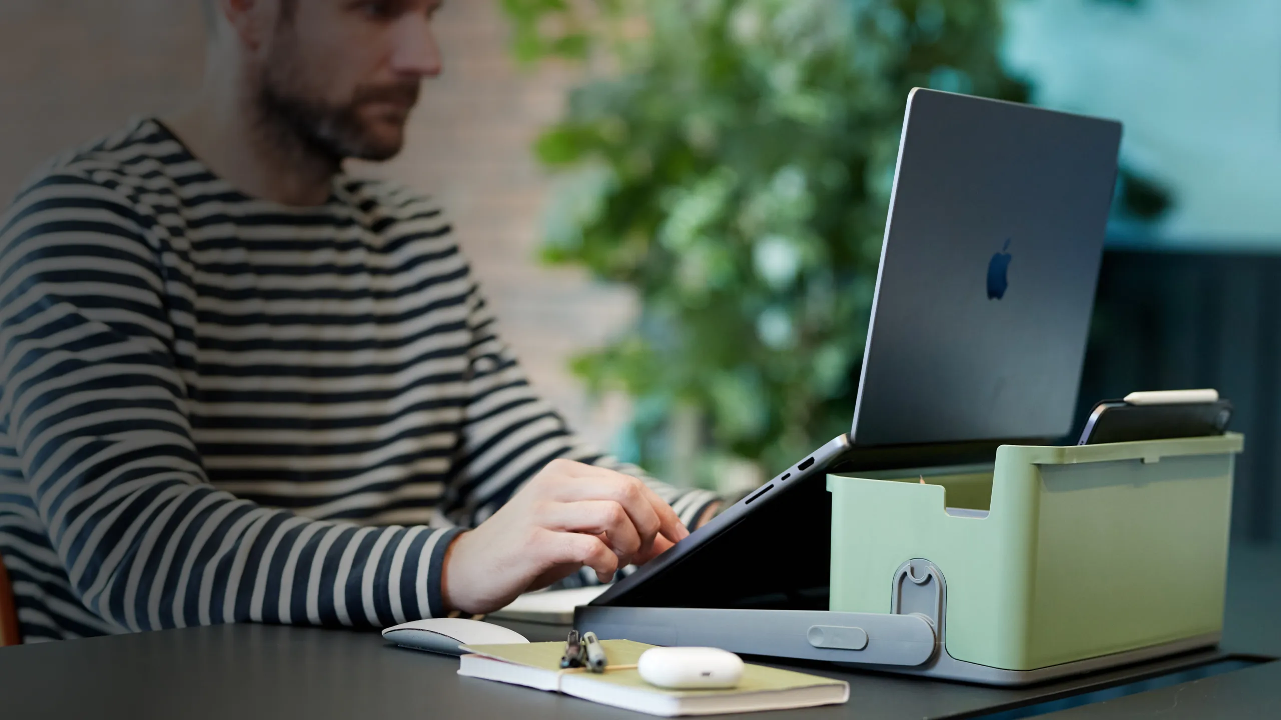 Un homme assis à une table utilisant un ordinateur portable situé dans un caddy Hotbox vert.