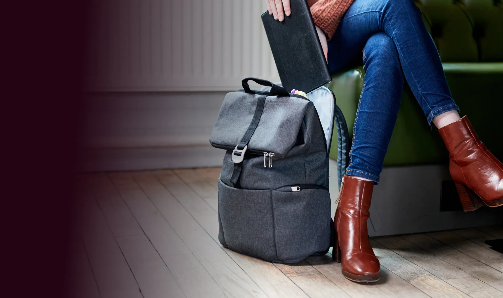 Une femme assise sur un canapé avec un sac à dos Shuttle gris à côté d'elle.