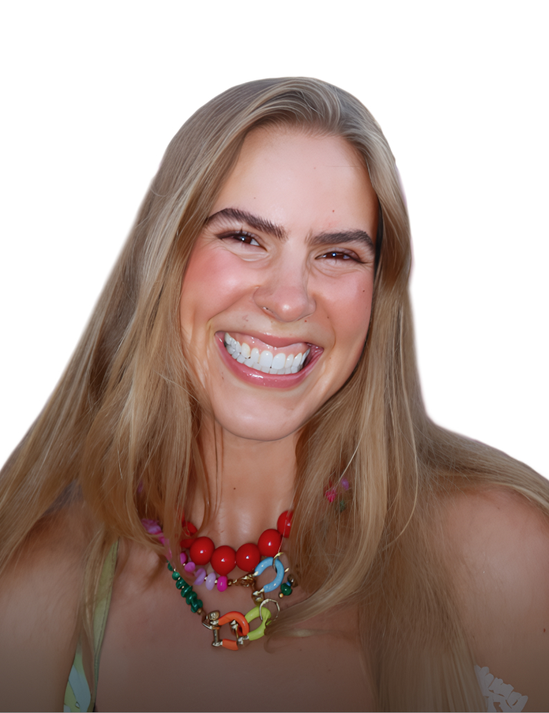 Smiling woman with long blonde hair wearing colorful beaded necklaces and a floral top.