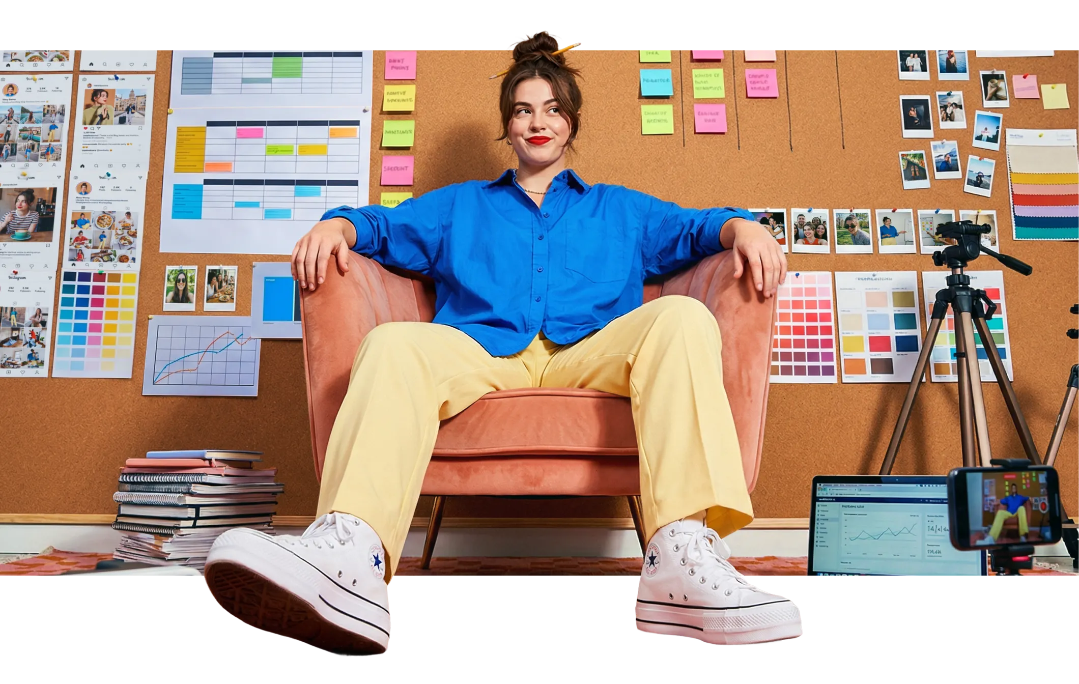Woman in blue shirt and yellow pants sitting on a pink chair in a creative workspace.