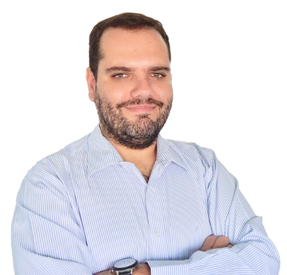 Man with short dark hair and beard wearing light blue striped shirt with arms crossed.