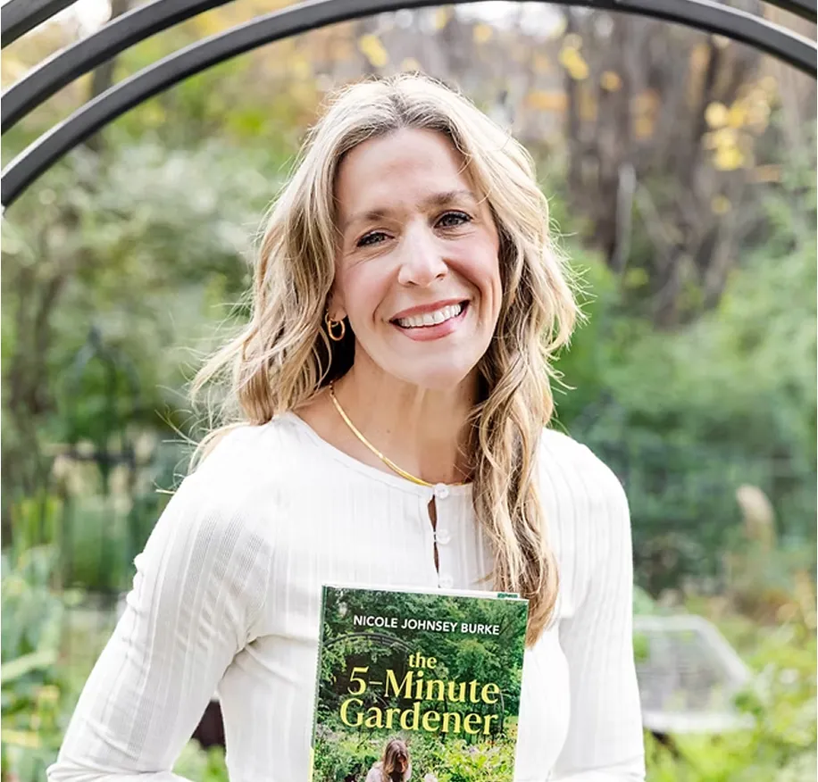 Smiling woman in white blouse holding the book 'The 5-Minute Gardener' by Nicole Johnsey Burke.
