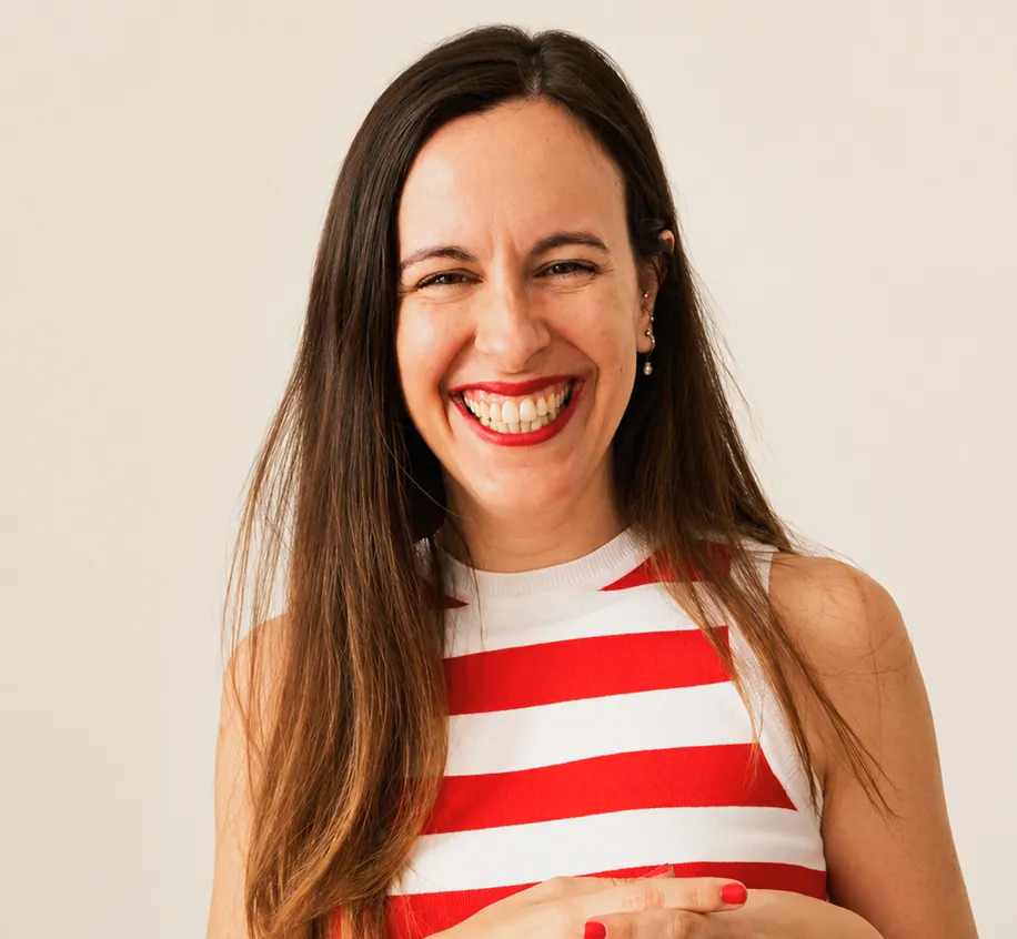 Smiling woman with long brown hair wearing red lipstick and a red-and-white striped sleeveless top.