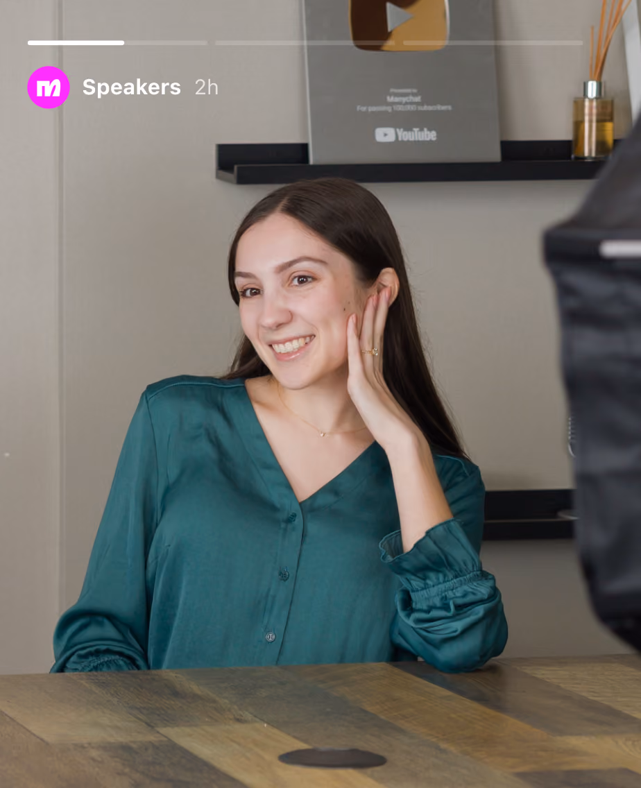 Smiling young woman in green blouse sitting at a wooden table with a YouTube play button award in the background.