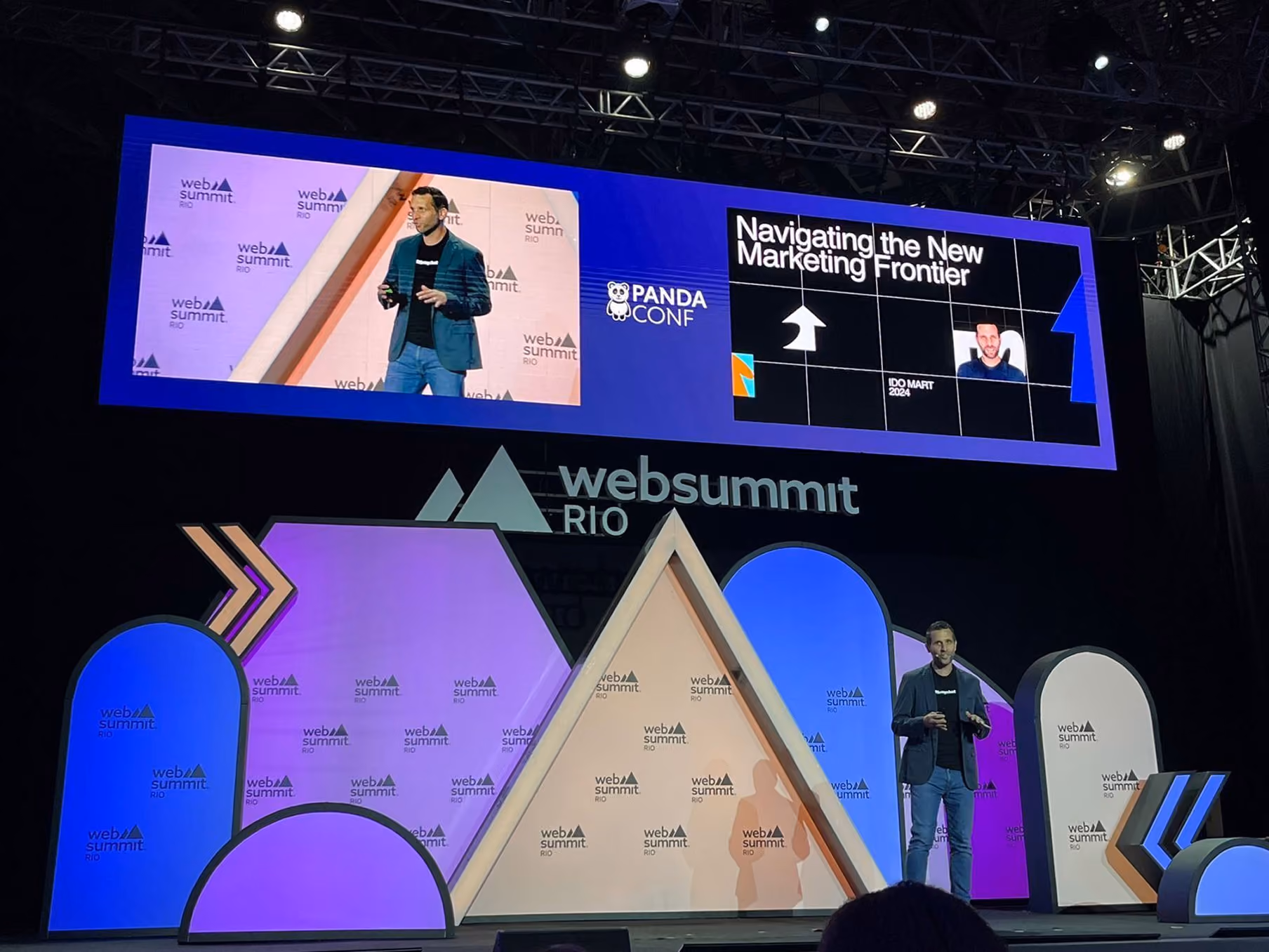 Speaker presenting on stage at Web Summit Rio with large screen showing Marketing Frontier slide.