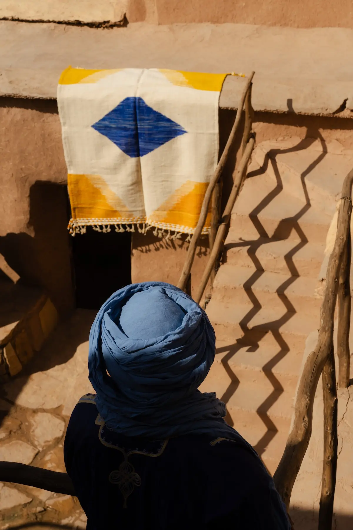 Amazigh berber walking in front of traditional rugs from Morocco