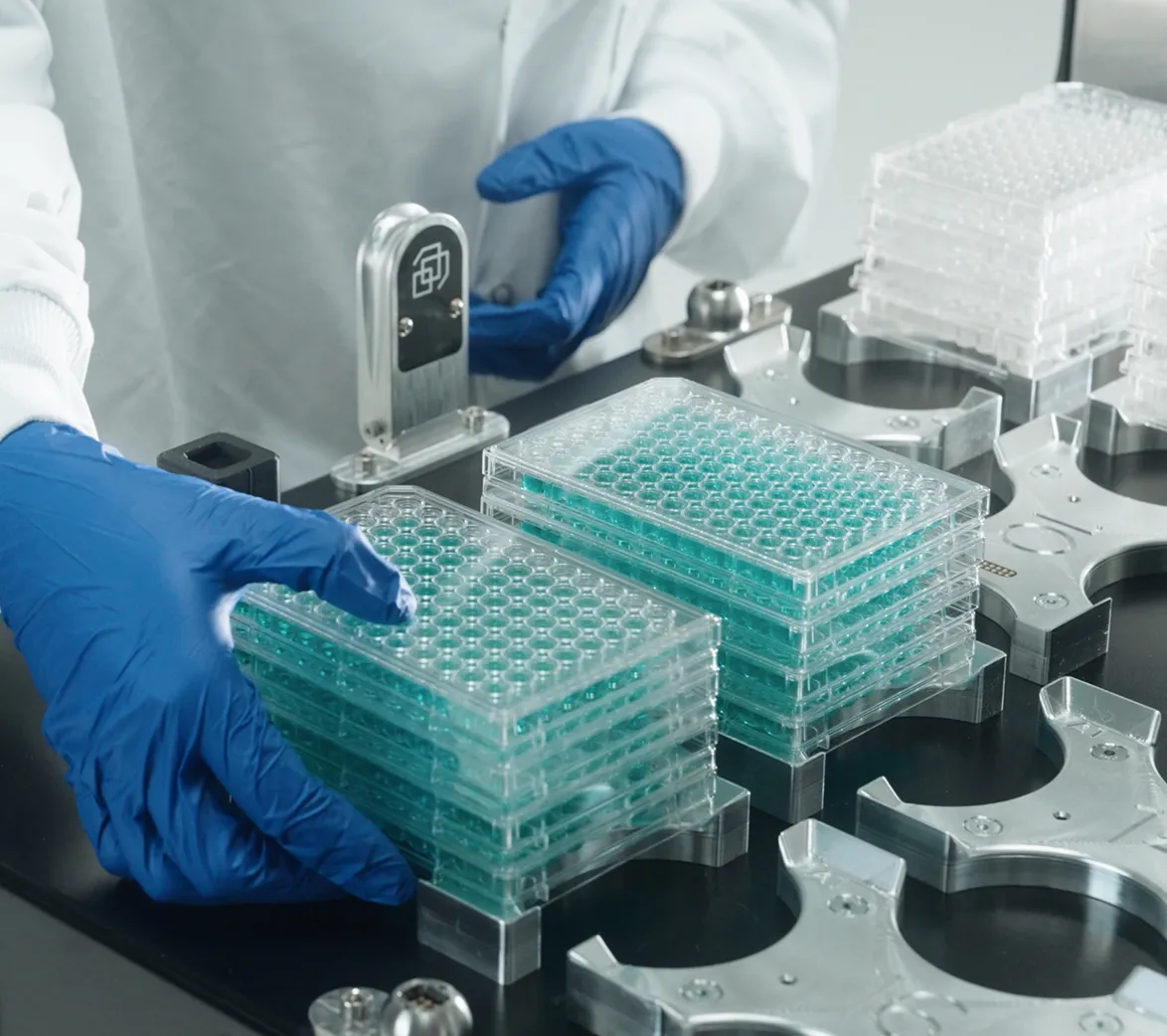 Biologist loading stacked microplates onto a self-driving lab workstation for automated experimentation