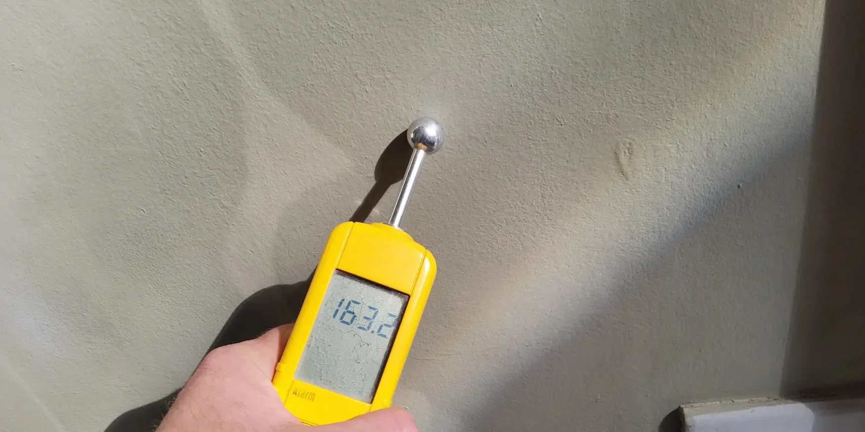 Vakman meet met een capacitieve vochtmeter het vochtgehalte in een muur