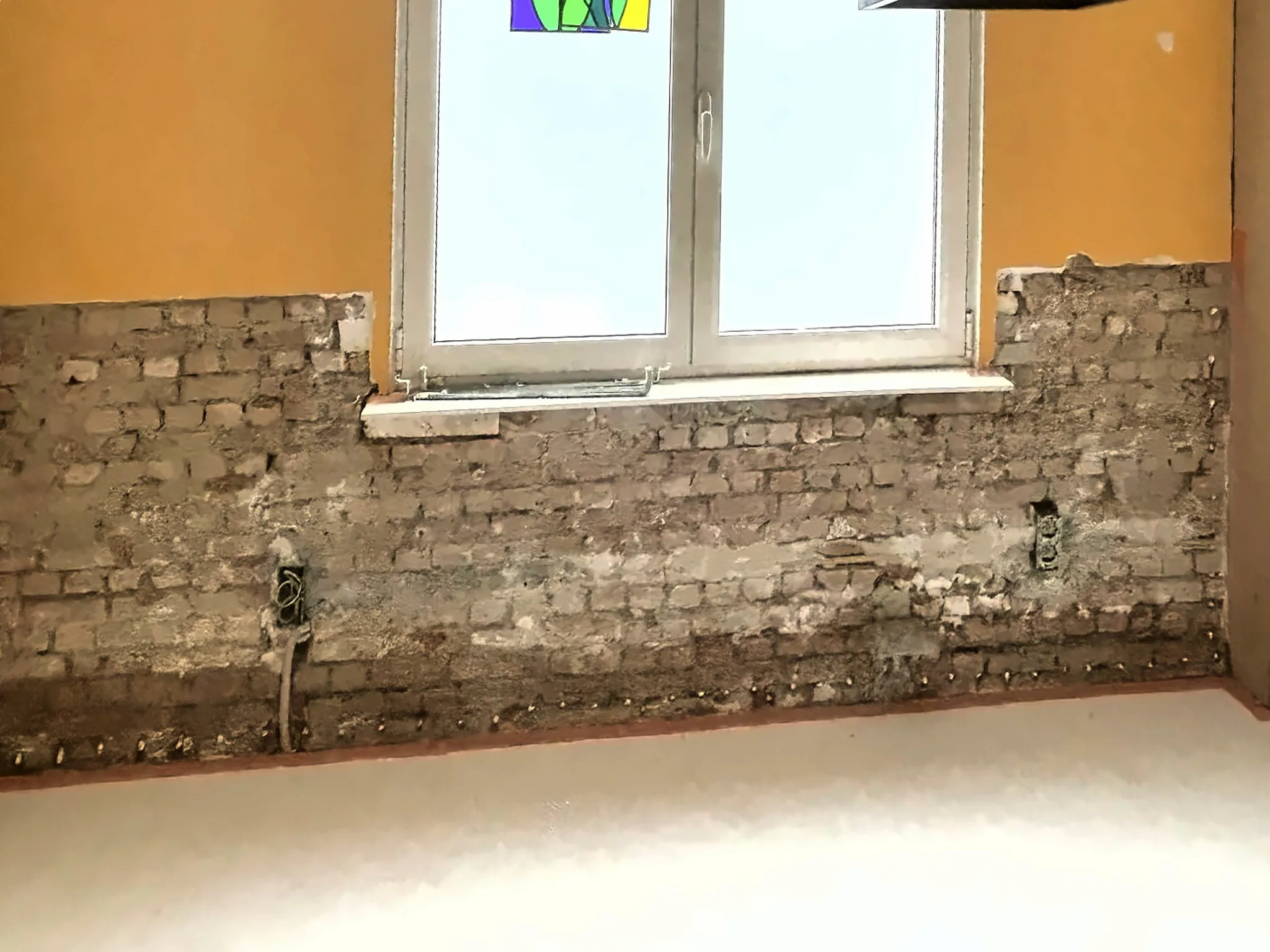 Dezelfde muur waarvan het aangetaste pleisterwerk is afgekapt tot op het metselwerk