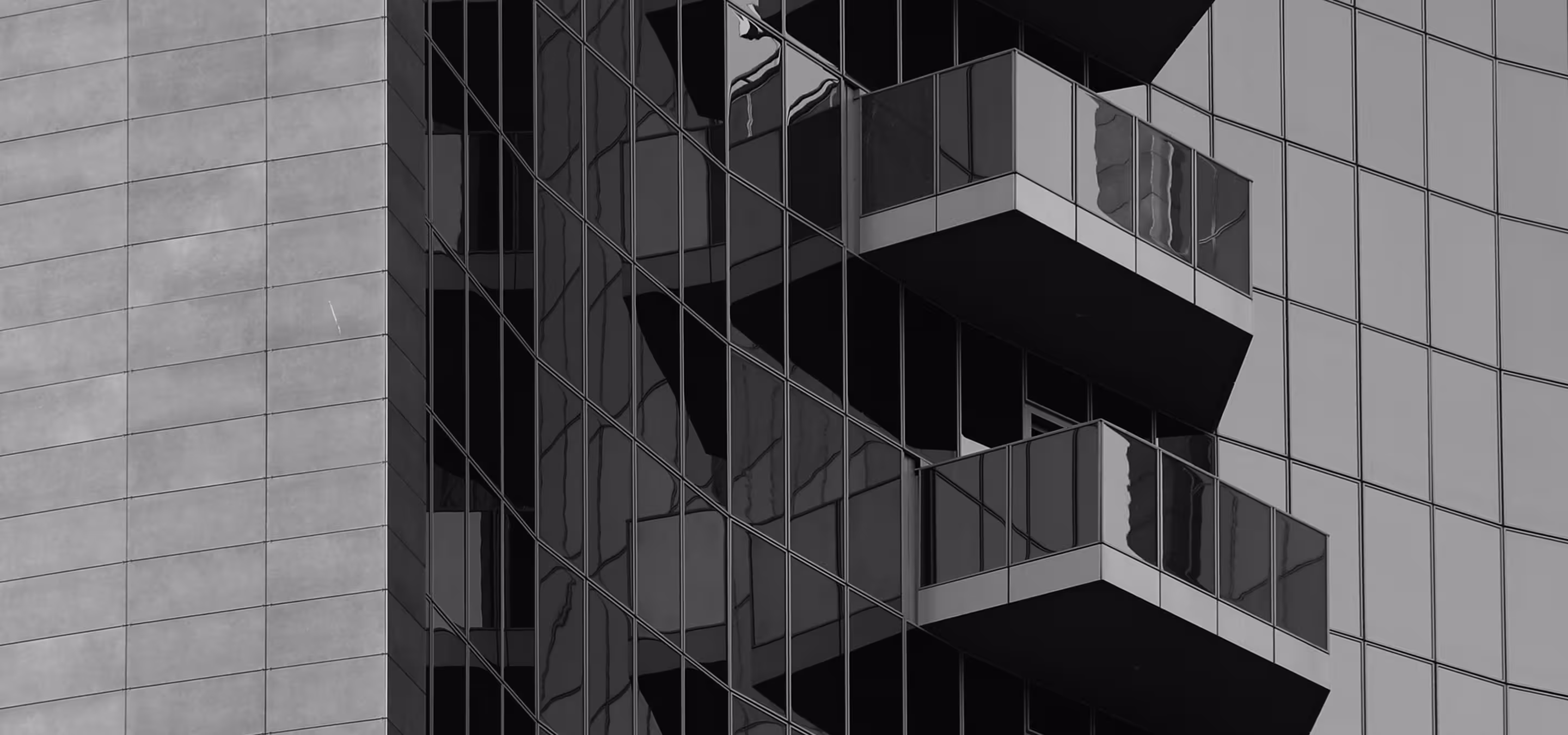 Close-up view of modern building's exterior with glass balconies and reflective windows.