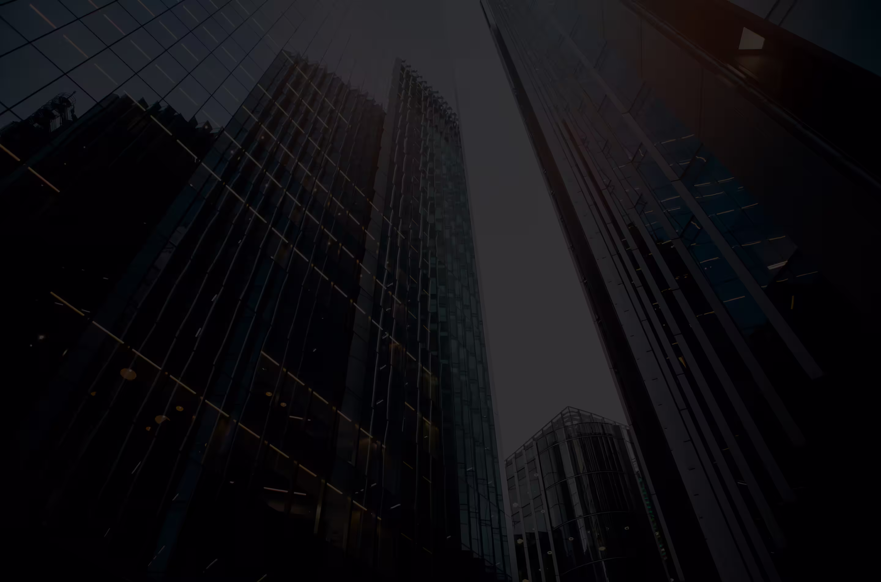 Upward view of modern glass skyscrapers with reflections under a cloudy sky.