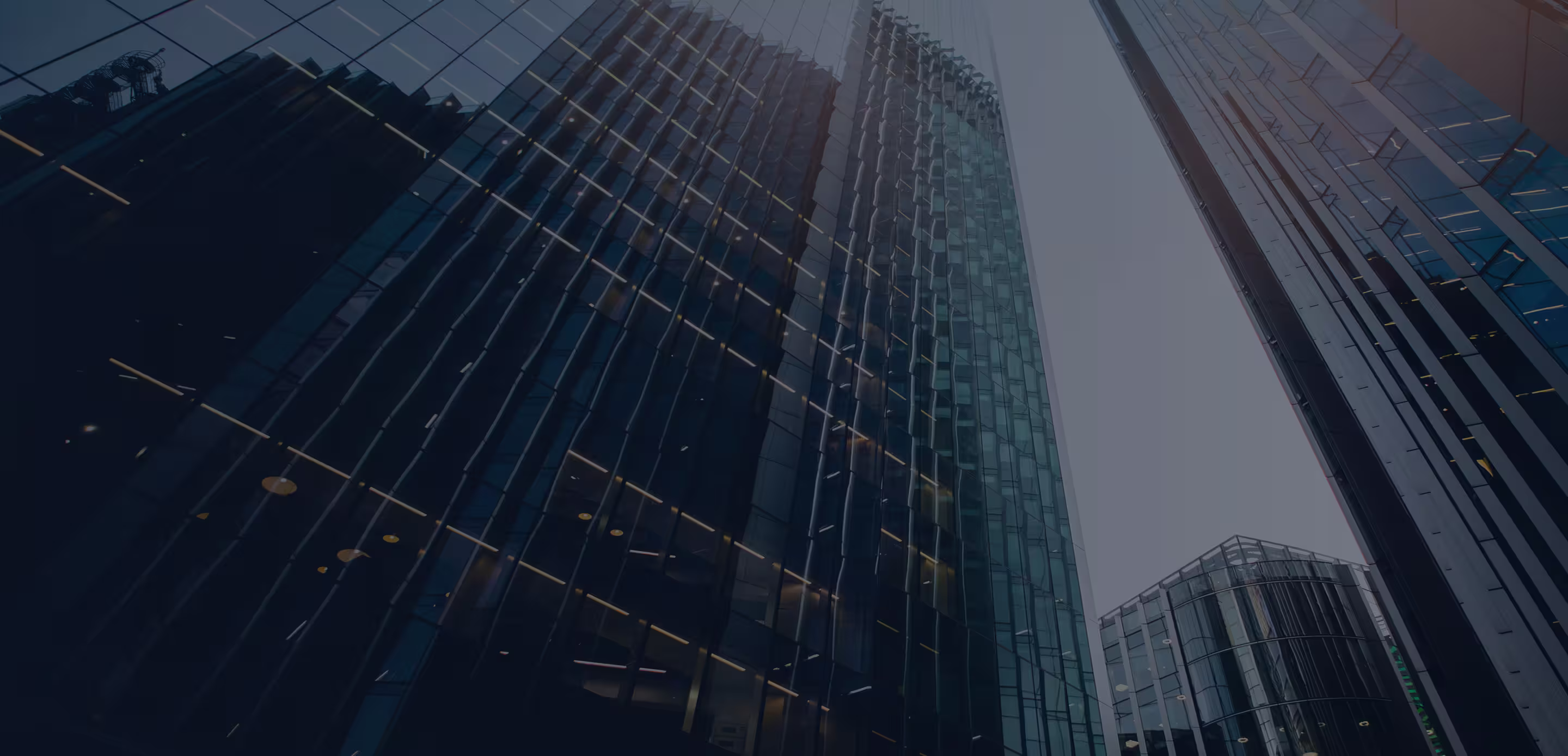 Upward view of tall glass office buildings reflecting light and sky.