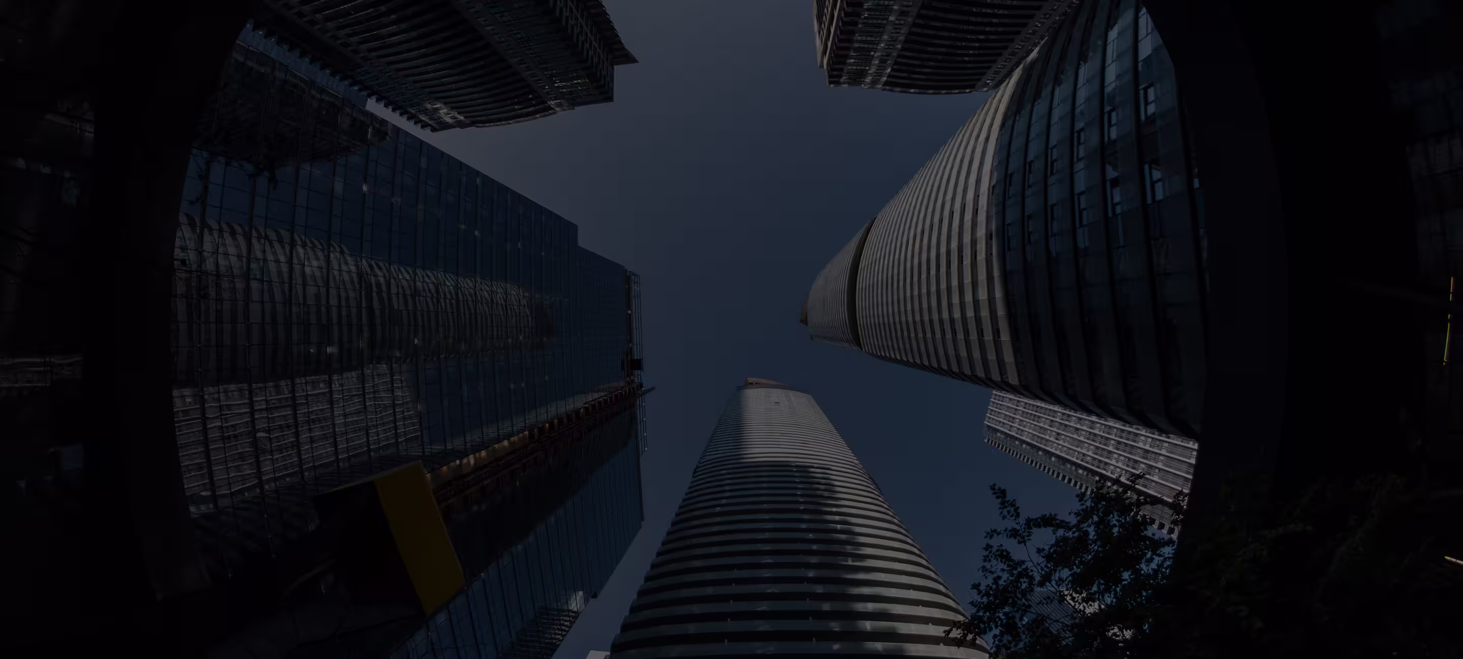 Looking up at tall modern skyscrapers against a clear blue sky in an urban setting.