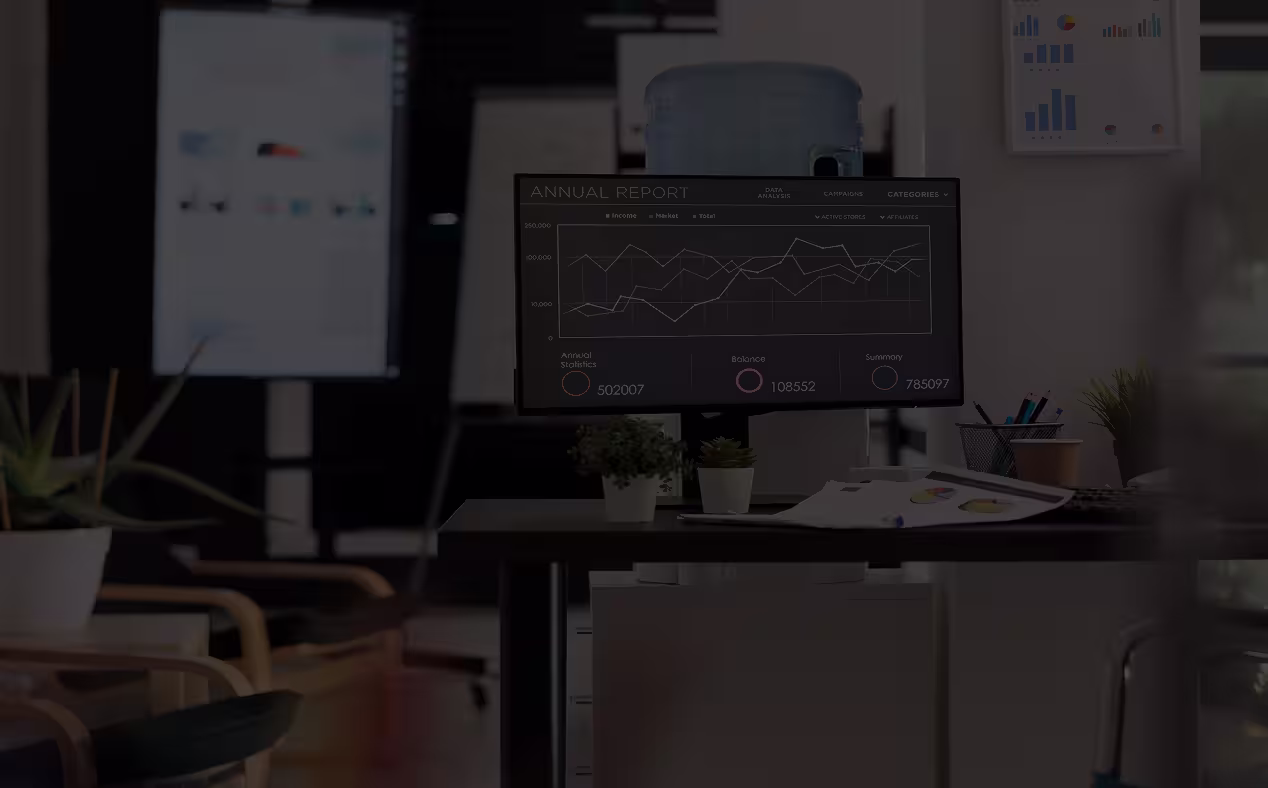 Computer monitor displaying an annual report with line graphs and summary statistics in a modern office setting.