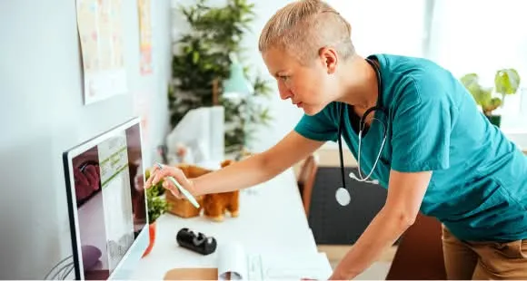 Provet veterinarian in teal scrubs examining medical records with stethoscope