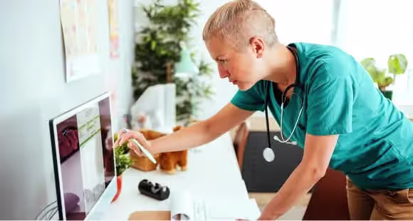 Provet veterinarian in teal scrubs examining medical records with stethoscope