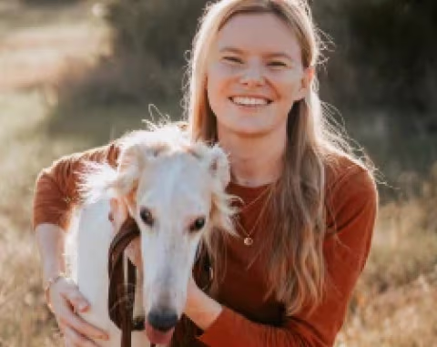 Provet: Smiling woman hugging white dog in golden field