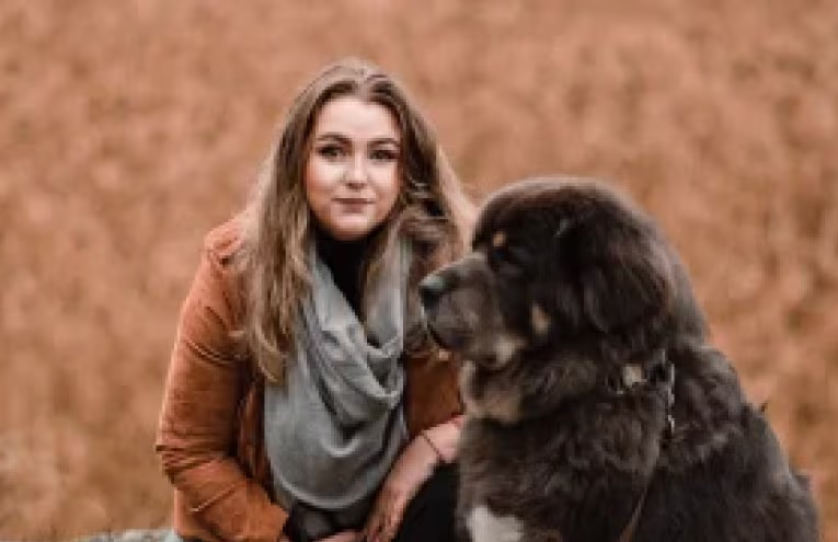 Provet companion: Woman in orange coat with loyal black dog outdoors