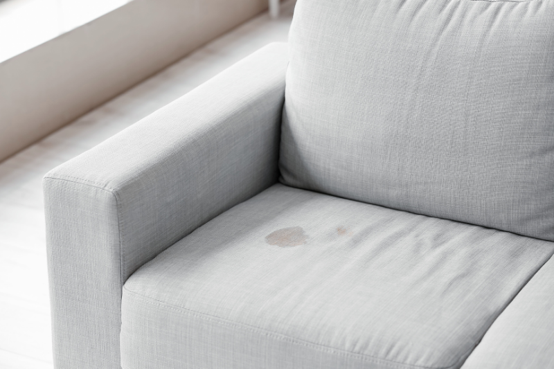 Light gray fabric sofa seat cushion with visible stains on it.