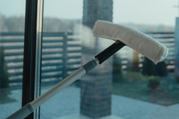Close-up of a window cleaning tool being used as part of routine maintenance services.