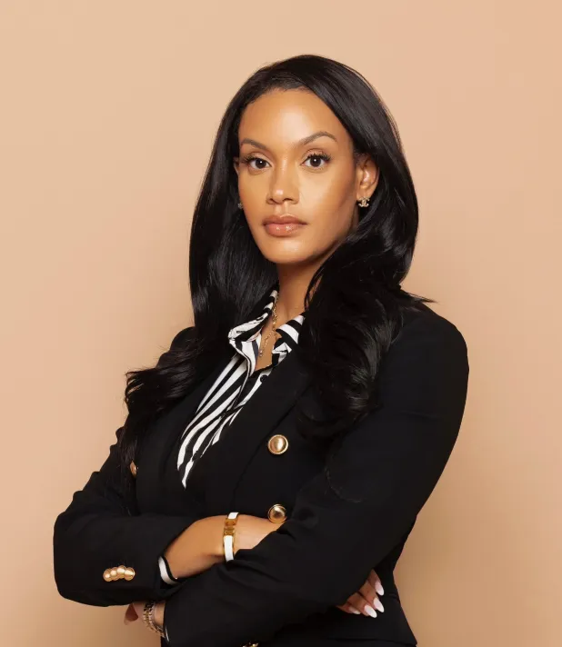 Woman in a black blazer posing with arms crossed.