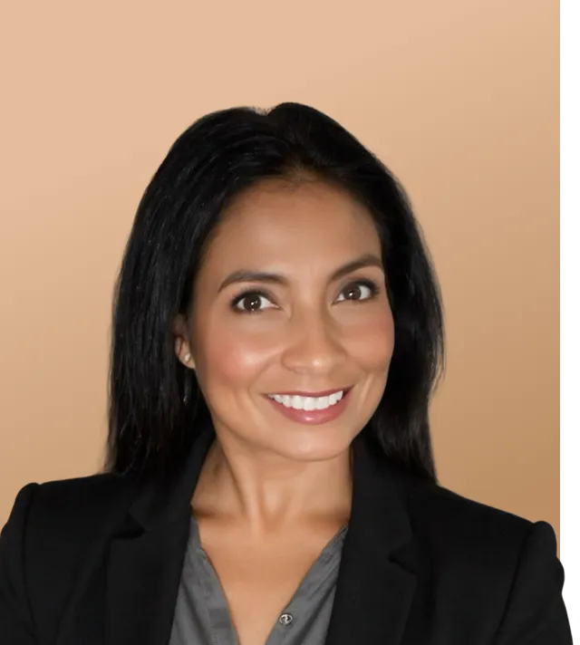 Woman in a blazer smiling in a studio portrait.