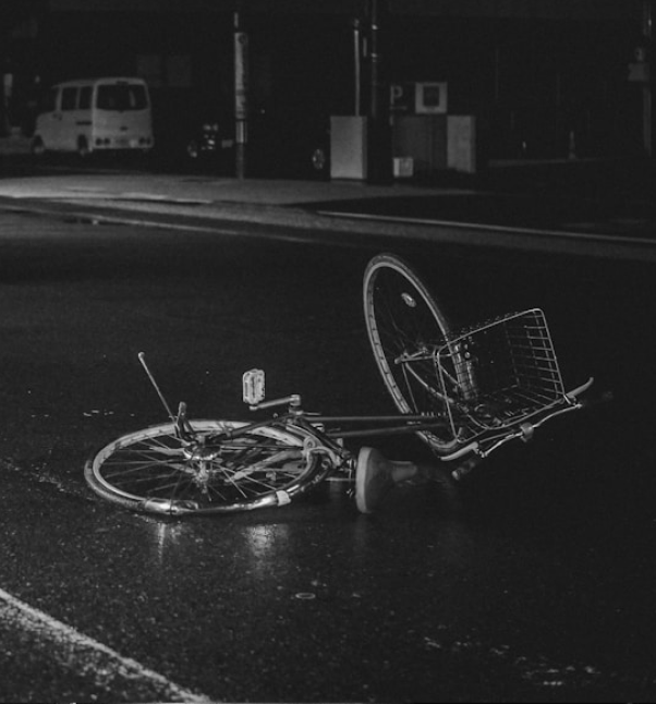 Bicycle lying on a wet road at night.