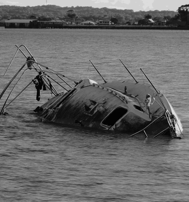 Partially sunken boat in shallow water.