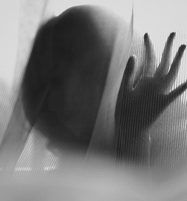Silhouette of a person’s hand behind a curtain.