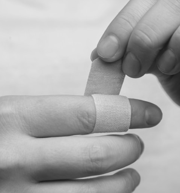 Hands applying a bandage to a finger.