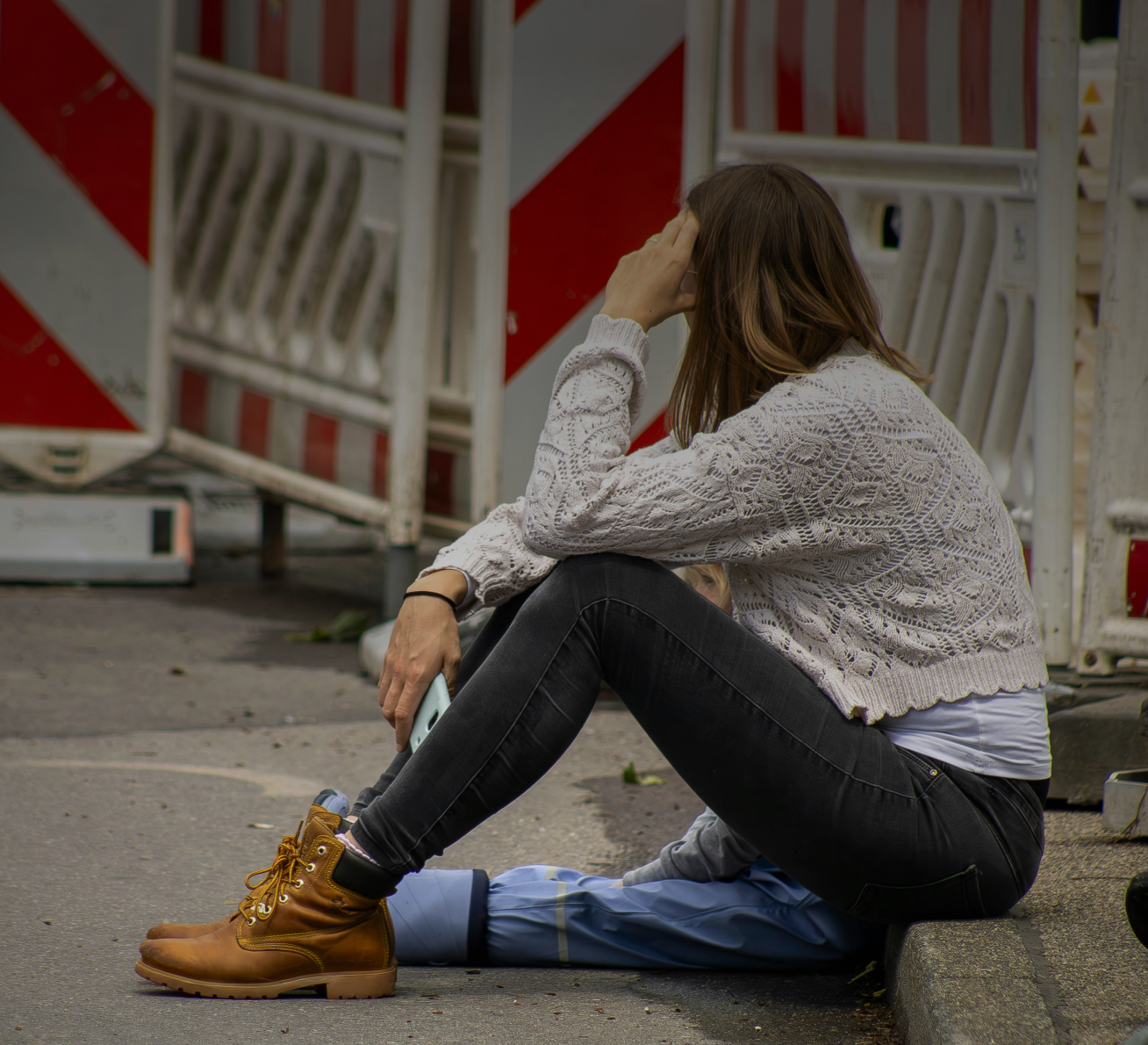 Woman holding her neck while looking at her phone near a car accident.