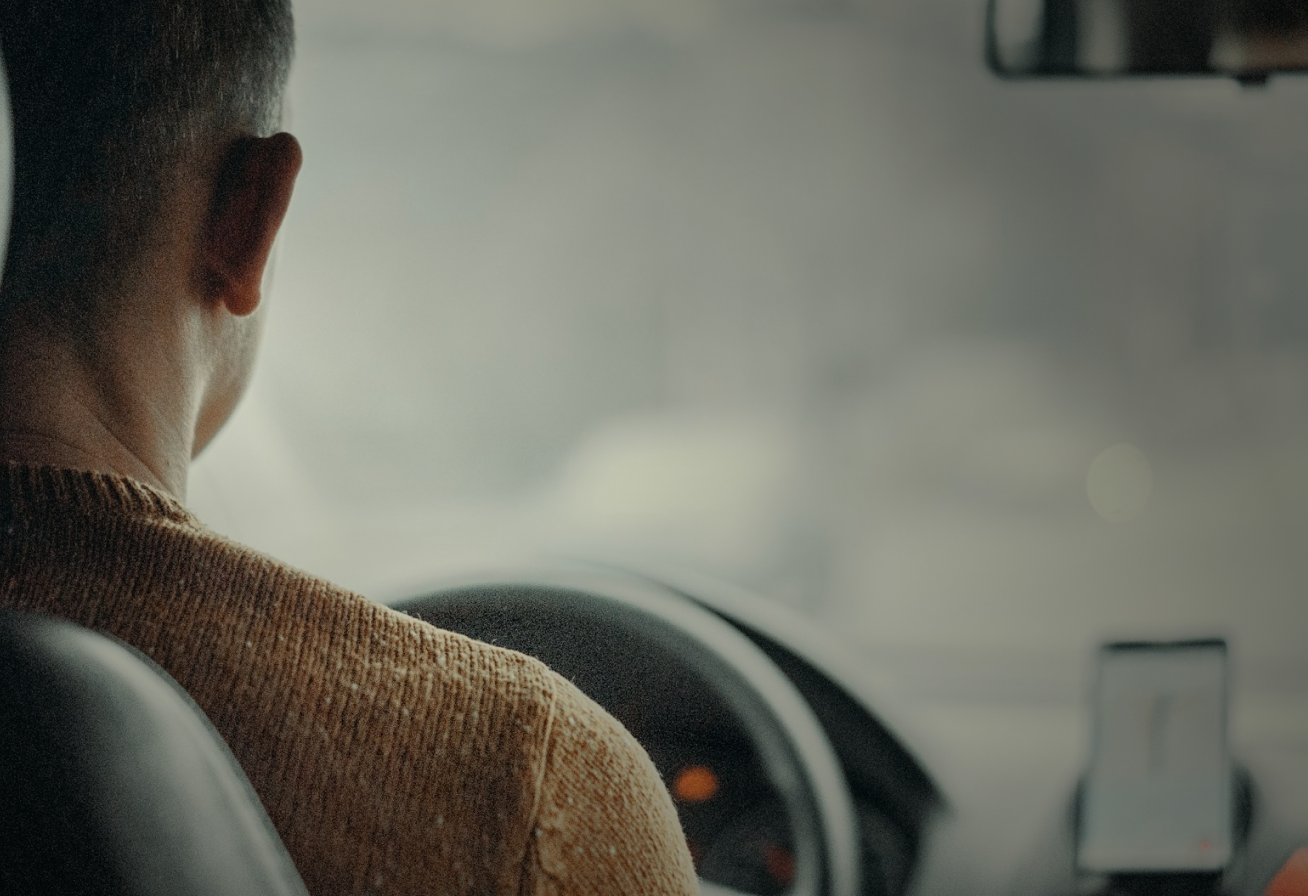 Woman holding her neck while looking at her phone near a car accident.