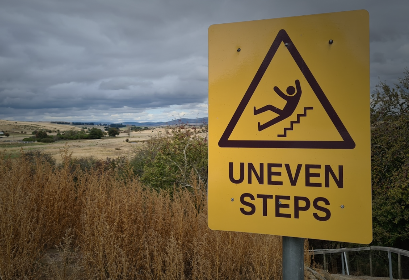 Woman holding her neck while looking at her phone near a car accident.