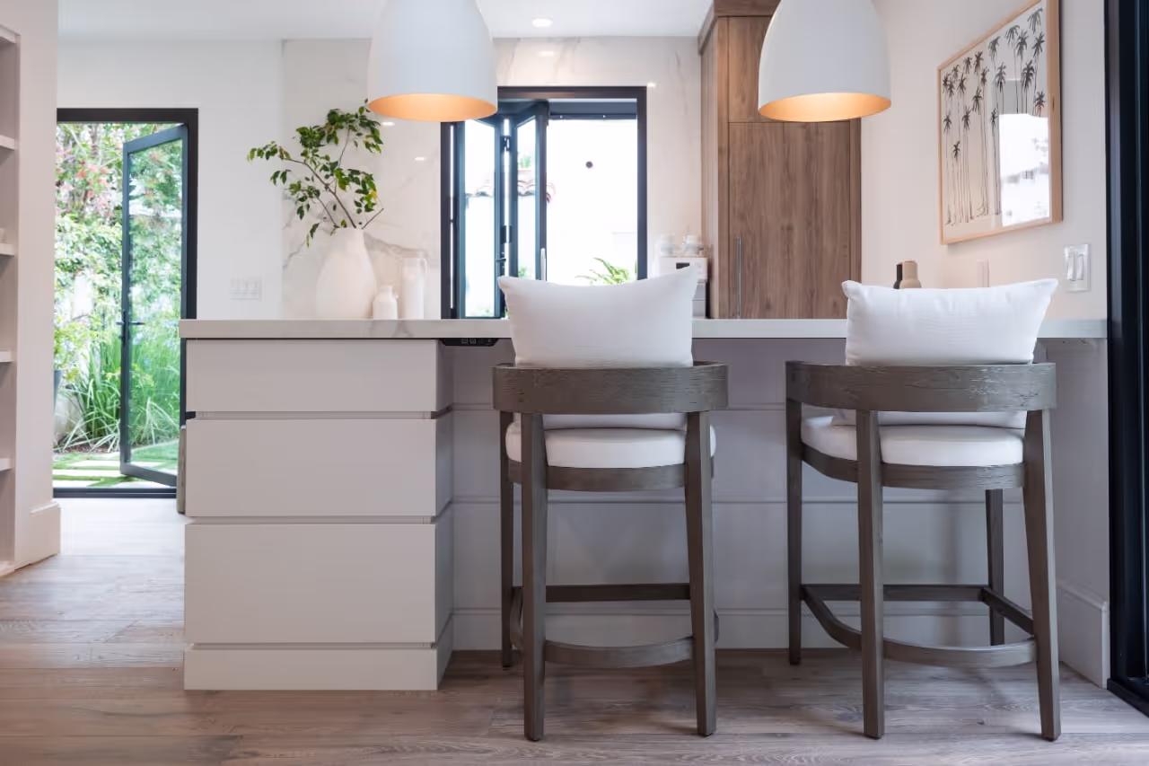 Stylish dining nook with custom cabinetry, modern pendant lighting, and large sliding doors opening to the garden from Brad Pitt’s Celebrity IOU makeover. Cabinetry by Marvel Cabinetry for HGTV’s Property Brothers: Celebrity IOU - Brad Pitt