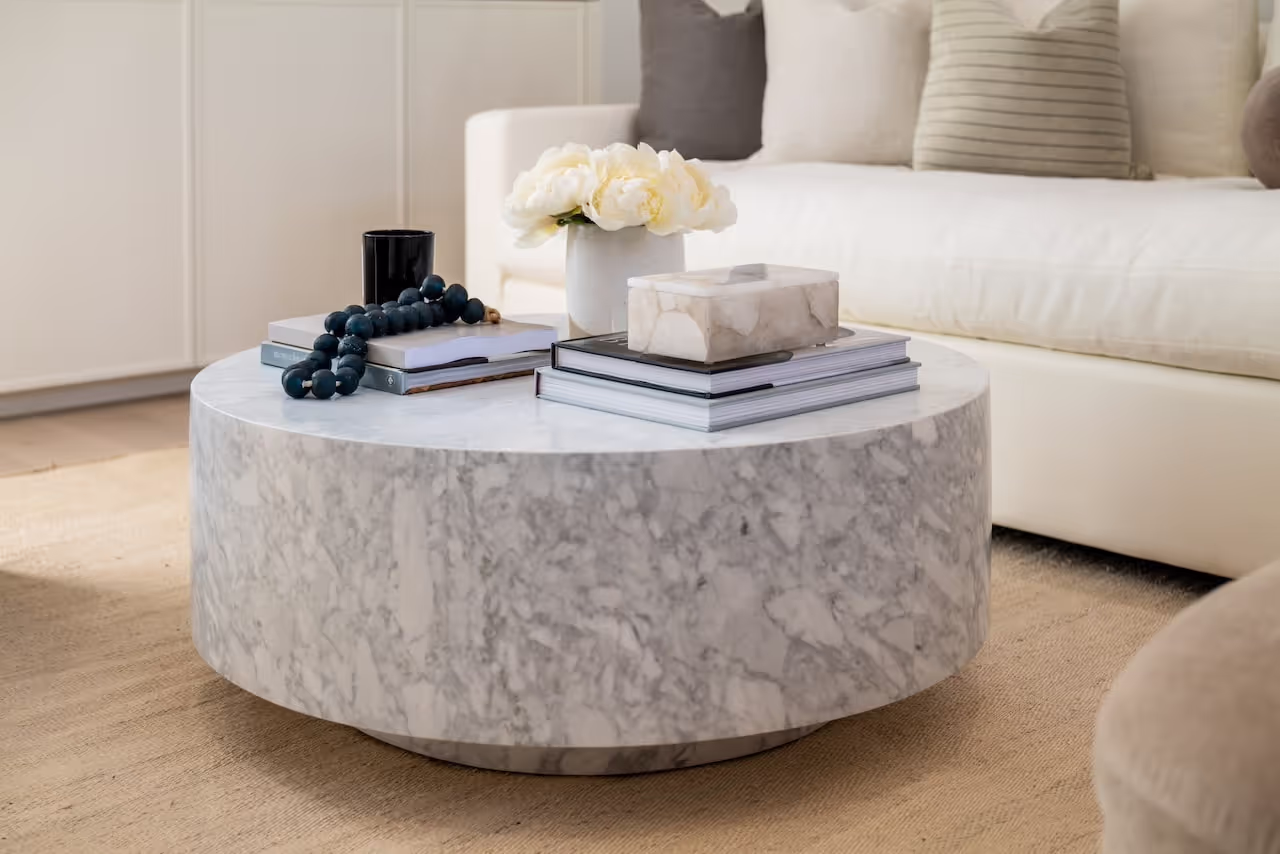 Round marble coffee table and soft neutral furnishings in a serene living room from Gwyneth Paltrow’s Celebrity IOU transformation. Cabinetry by Marvel Cabinetry for HGTV’s Property Brothers: Celebrity IOU - Gwyneth Paltrow