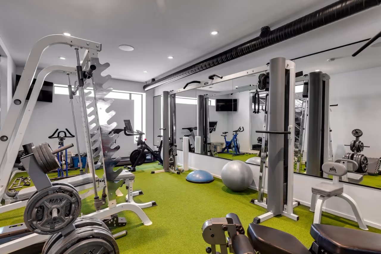 Home gym featuring custom built-in storage cabinetry, integrated mirrors, and modern fitness-area millwork. Cabinetry by Marvel Cabinetry.