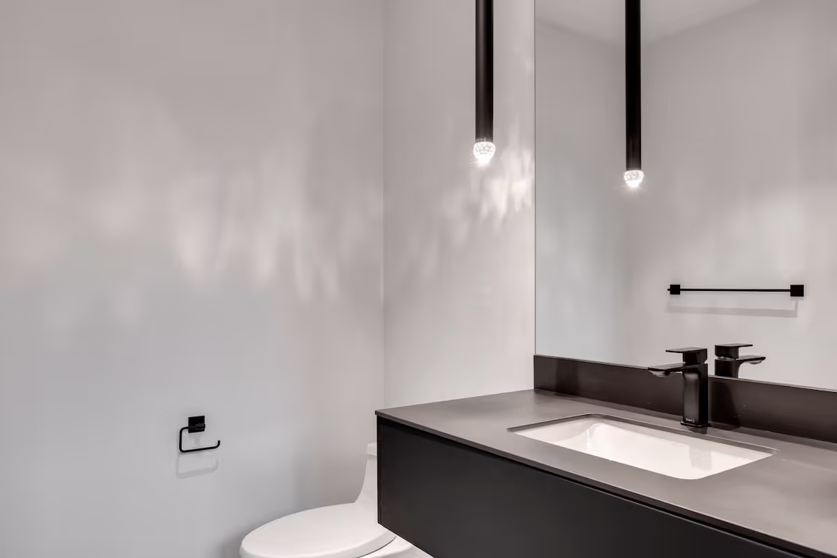 Bathroom featuring modern floating vanity cabinetry, integrated lighting, and minimalist matte-black fixtures. Cabinetry by Marvel Cabinetry.