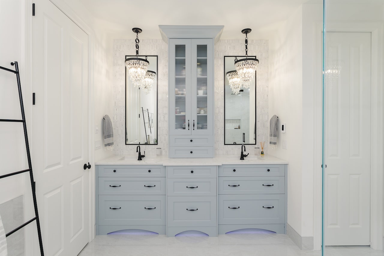 Luxury bathroom featuring double-sink custom vanity cabinetry, tall storage tower, and elegant lighting. Cabinetry by Marvel Cabinetry.
