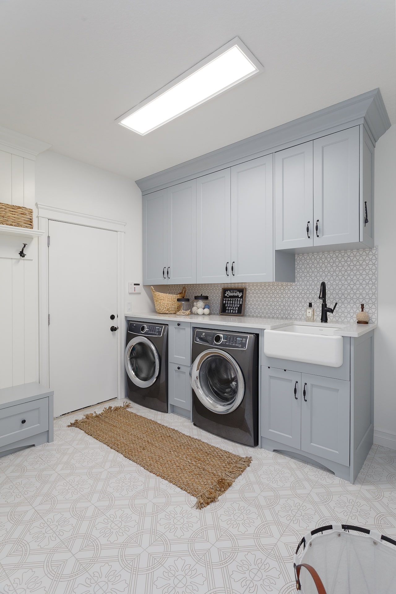 Laundry room with custom grey cabinetry, full-height storage, and integrated washer–dryer space. Cabinetry by Marvel Cabinetry.