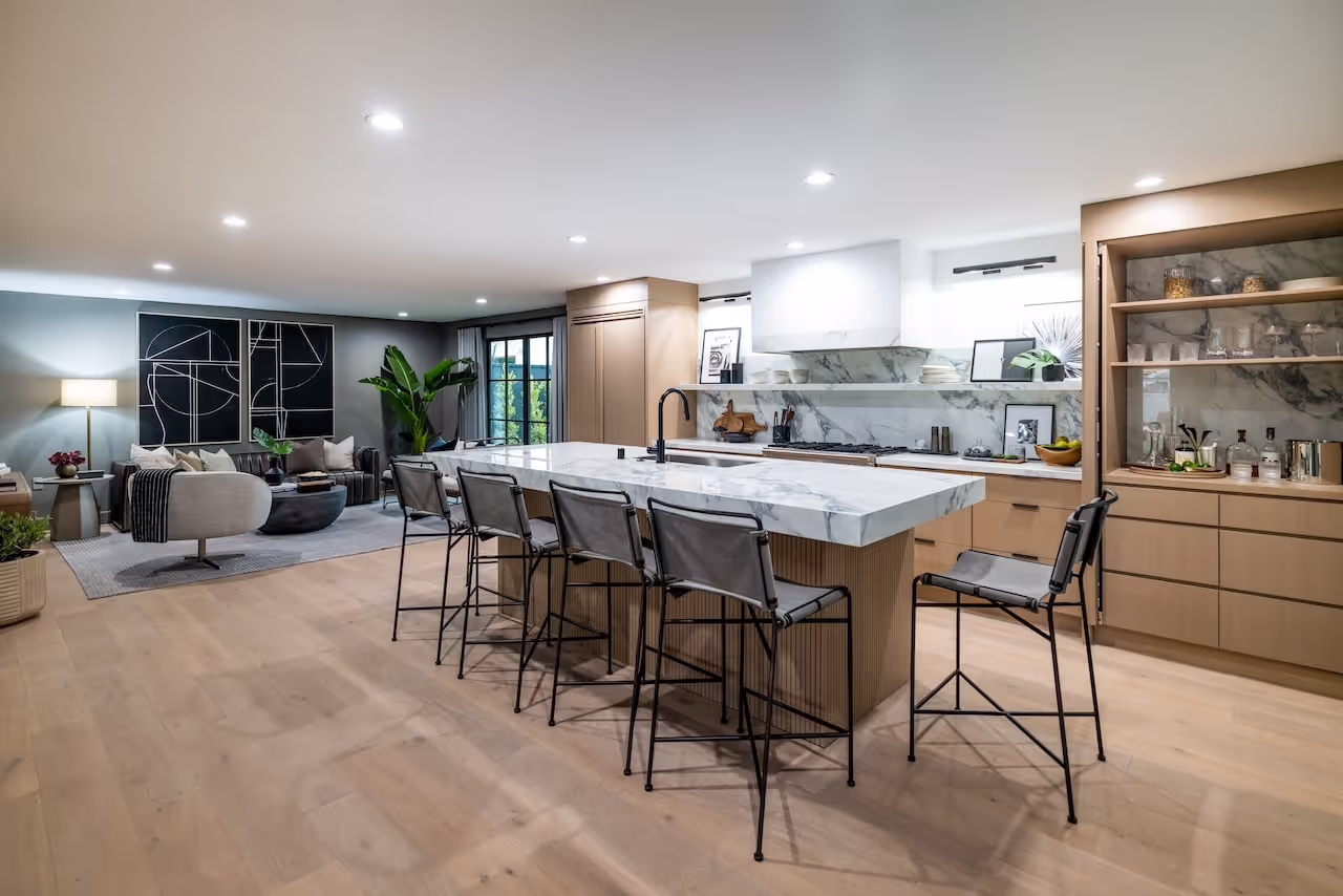 Expansive kitchen and lounge area with custom cabinetry, integrated shelving, and light wood finishes designed for Kevin Hart’s Celebrity IOU makeover. Cabinetry by Marvel Cabinetry for HGTV’s Property Brothers: Celebrity IOU - Kevin Hart