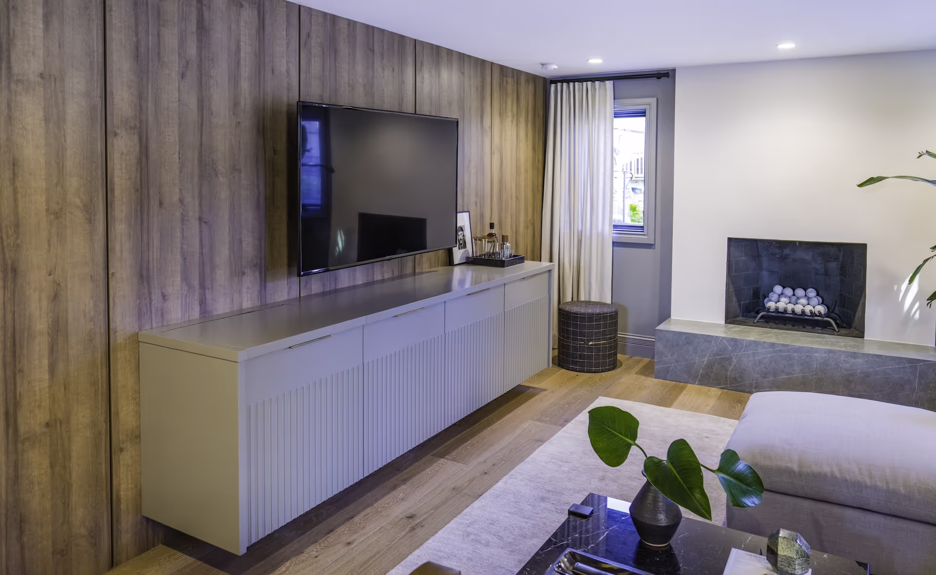 Custom entertainment wall with built-in cabinetry, wood paneling, and integrated shelving in Melissa McCarthy’s Celebrity IOU remodel. Cabinetry by Marvel Cabinetry for HGTV’s Property Brothers: Celebrity IOU - Melissa McCarthy