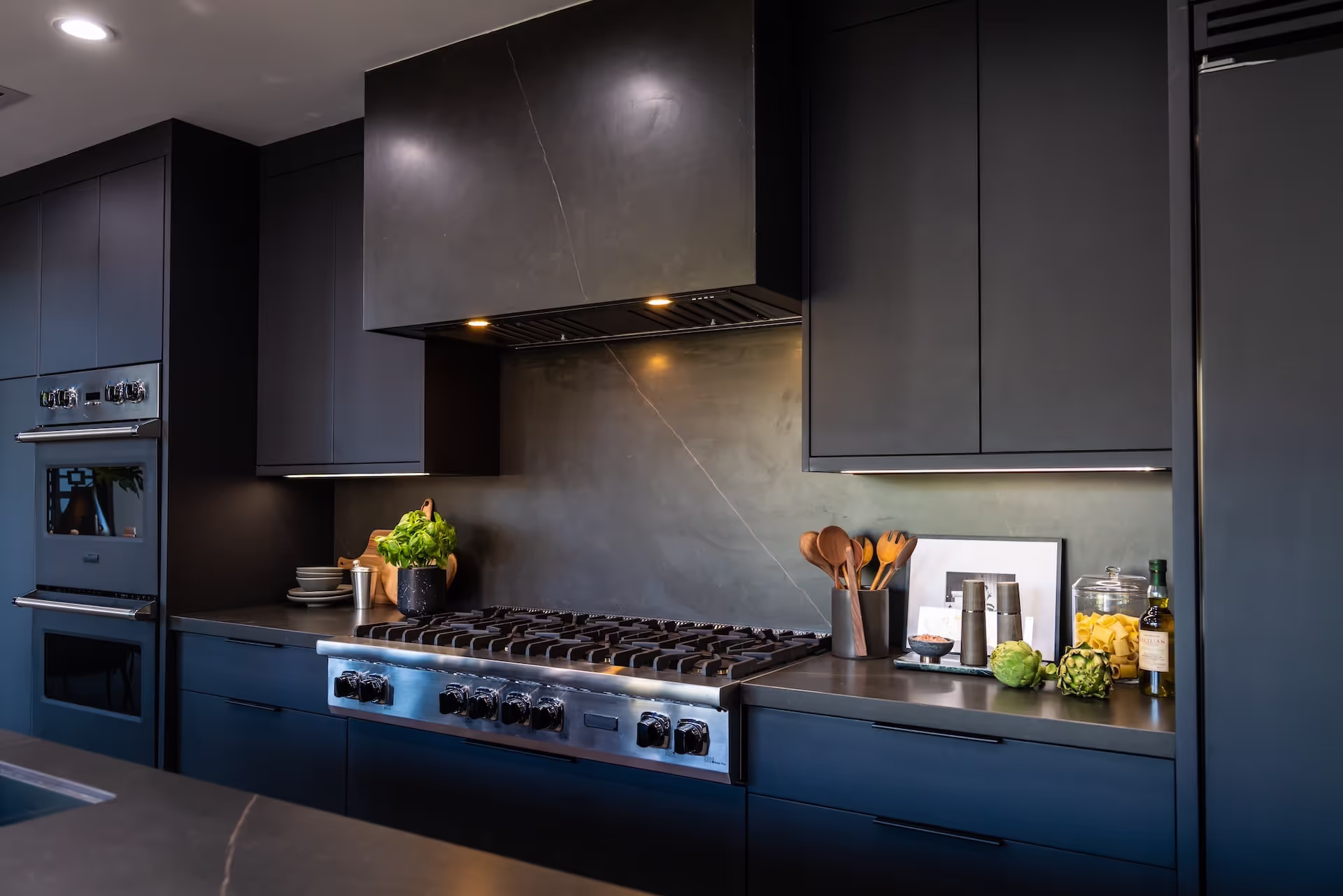 Luxury cooking zone featuring professional range, black cabinetry, and stone backsplash from LeAnn Rimes’ Celebrity IOU project. Cabinetry by Marvel Cabinetry for HGTV’s Property Brothers: Celebrity IOU - LeAnn Rimes