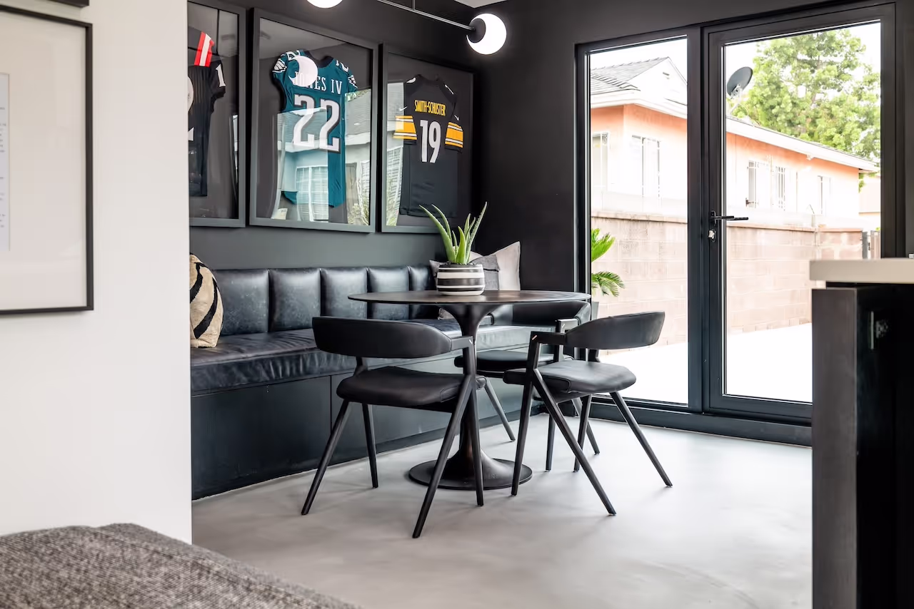 Dining nook and lounge area with custom built-ins, black cabinetry, sports jerseys, and modern interior finishes for Snoop Dogg’s Celebrity IOU reveal. Cabinetry by Marvel Cabinetry for HGTV’s Property Brothers: Celebrity IOU - Snoop Dogg