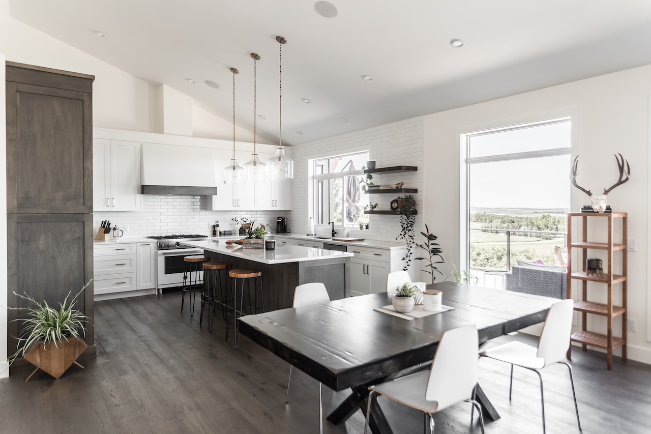 Bright open-concept kitchen with custom white cabinetry, wood accents, large island, and modern dining area. Cabinetry by Marvel Cabinetry.