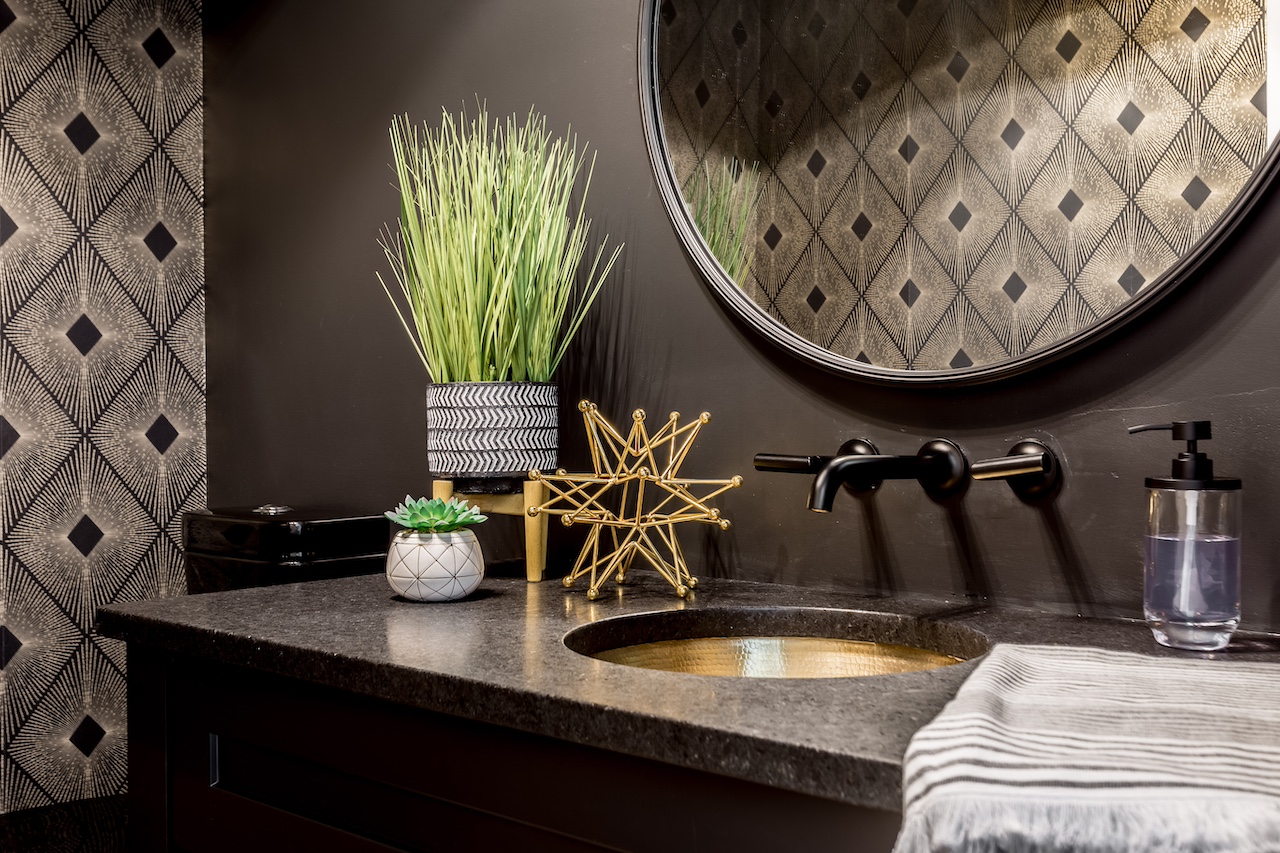 Powder room with custom dark vanity, gold sink, decorative tile accent wall, and elegant millwork finishes. Cabinetry by Marvel Cabinetry.