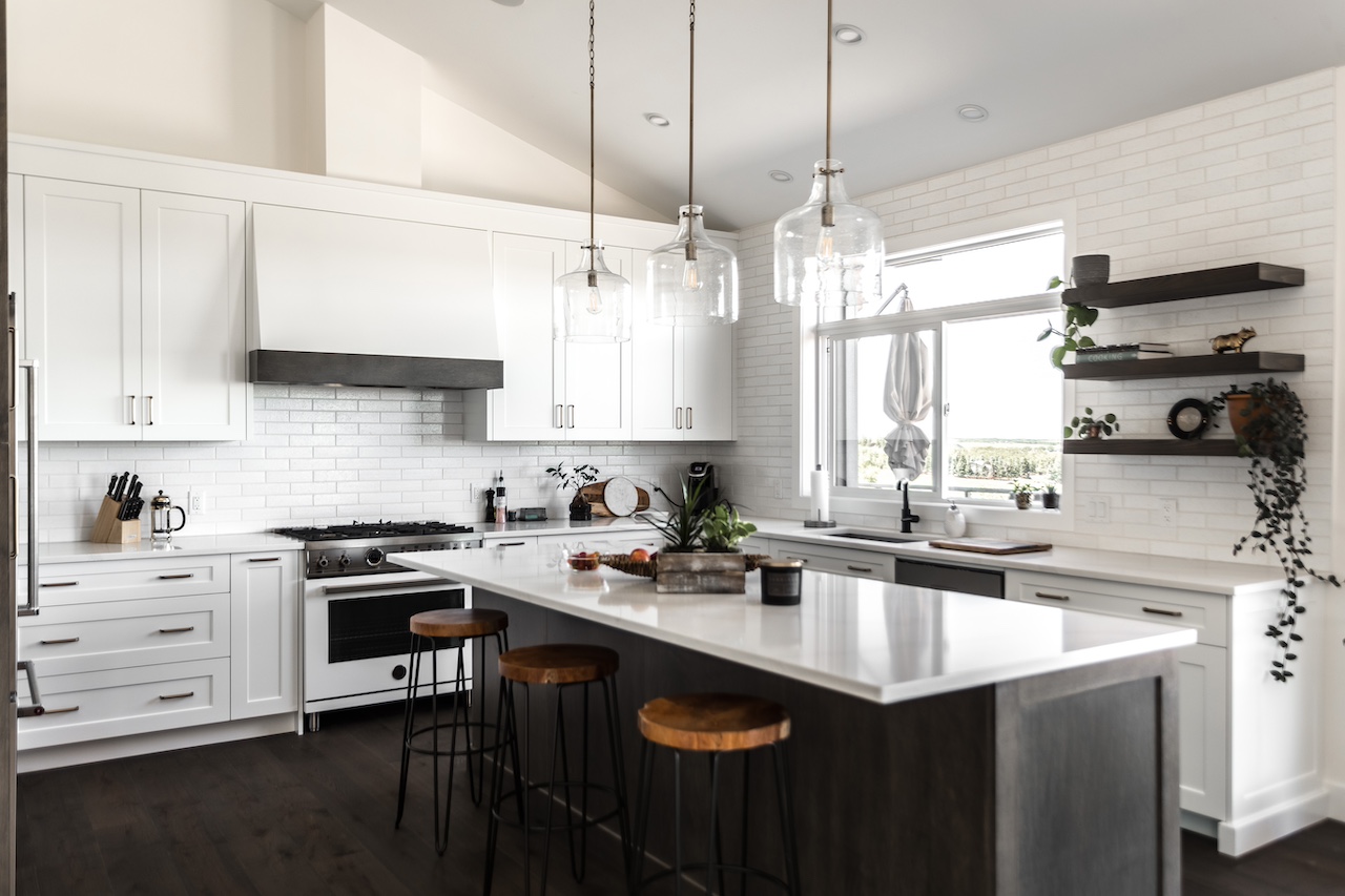 White kitchen featuring shaker cabinetry, custom island with dark millwork, open shelving, and pendant lighting. Cabinetry by Marvel Cabinetry.