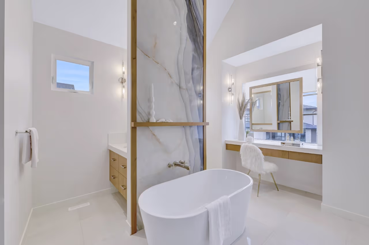 Spa-style bathroom with freestanding tub, marble feature wall, and custom vanity cabinetry. Cabinetry by Marvel Cabinetry.