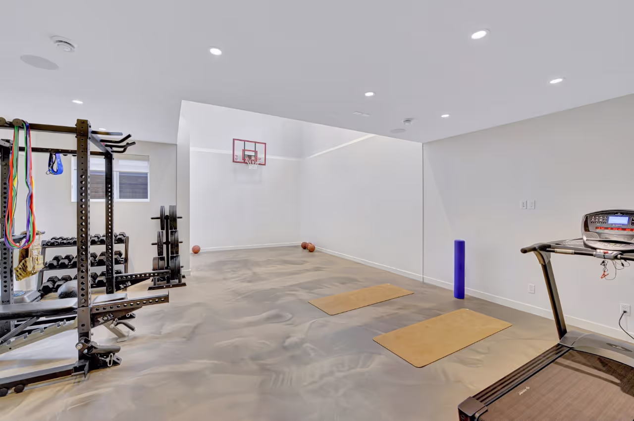 Home gym with custom storage cabinetry, durable flooring, and multi-use workout zones. Cabinetry by Marvel Cabinetry.